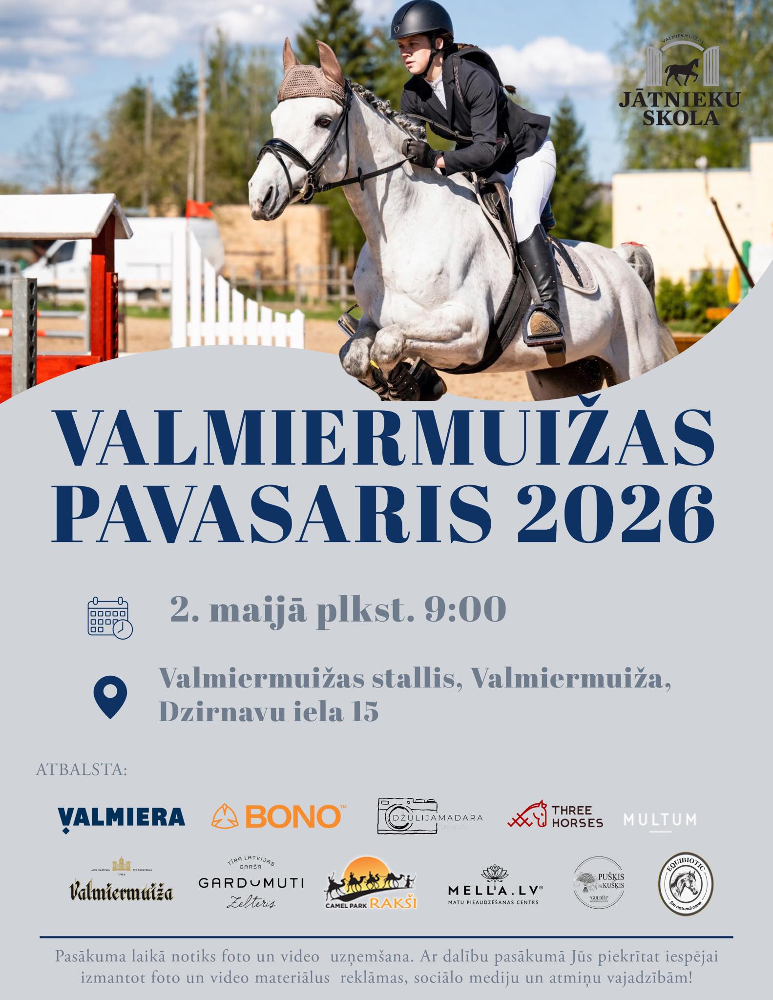 Afiša jātnieku sacensībām “Valmiermuižas pavasaris 2026”. Augšdaļā redzama jātniece uz balta zirga lēciena brīdī, labajā augšējā stūrī “Jātnieku skolas” logo. Tekstā norādīts, ka pasākums notiks 2. maijā plkst. 9.00